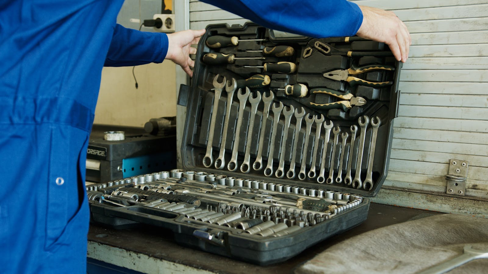 Mechanic organizing a comprehensive tool set for vehicle maintenance in a workshop setting.