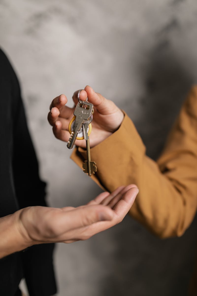 Two adults exchanging house keys, symbolic of property transfer or rental agreement.